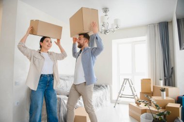 Genç bir çift kafalarında karton kutular taşıyorlar. Parlak, modern bir dairede. Yeni evlerine taşınmalarını kutlarken gülümsüyorlar.