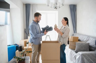 Genç çift ev eşyalarını karton kutulara dolduruyor, taşınmaya hazırlanıyor ve yeni bir dairede yeni bir başlangıç yapıyorlar.