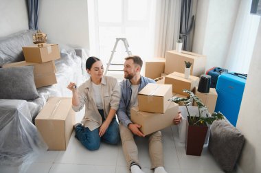 Genç çift yeni eve taşınmayı kutluyorlar, ellerinde anahtarlar ve karton kutularla yeni bir hayata başlıyorlar.