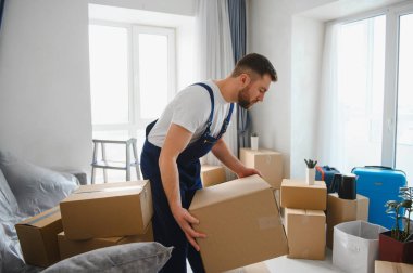 Nakliye kartonlarında yeni bir eve eşyalar taşıyan profesyonel bir nakliyeci. Konut teslimatı ve taşınma hizmeti kavramı