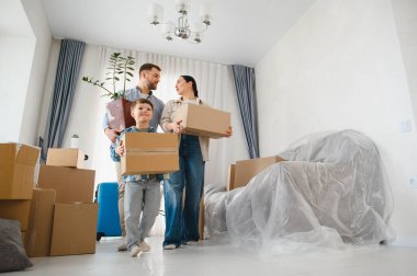 Ebeveyn ve oğul karton kutular ve bir çiçek taşıyorlar, yeni bir eve taşınıyorlar, yeni bir hayata başlıyorlar.