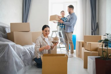 Mutlu bir aile yeni bir daireye taşınıyor, aileler ve çocuklar karton kutulardan kişisel eşyalarını boşaltıyorlar, yaşam tarzlarını değiştiriyorlar.