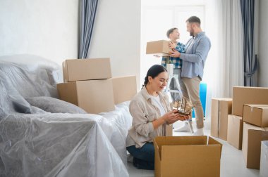 Aile taşınıyor, yeni boş dairelerinde karton kutularla birlikte eşyaları boşaltıyorlar. Taşınma ve birliktelik kavramları