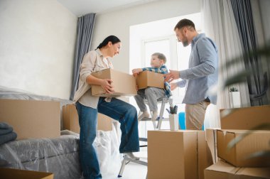 Mutlu aile yeni bir daireye taşınıyor. Ebeveynler ve çocuklar kutuları açıyor ve taşınmayı kutluyorlar