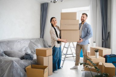 Mutlu genç çift yeni bir daireye taşınıyor, birlikte karton kutular taşıyorlar. Eşyaları modern yaşam alanlarına yerleştirmek