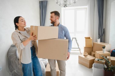 Mutlu çift yeni eve taşınıyor, karton kutular taşıyor, ev sahipliğini ve geleceği kutluyorlar.