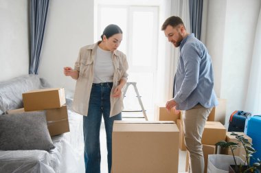 Karton kutuları paketleyen çift, yeni bir daireye taşınmaya hazırlanıyor, taşınma günü boyunca eşyaları düzenliyor.