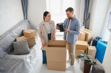 Yeni bir daireye taşındıktan sonra kutuları açan mutlu çift. Karton bir kutudan su ısıtıcısı çıkarıyorlar.