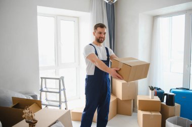 Mover çalışanı bir kutu taşıyor, modern bir dairede taşınmaya yardım ediyor. Profesyonel dağıtım ve taşıma hizmetleri kavramı