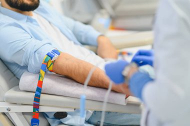 Kan bağışı yapan bir adam, klinikte damar içi infüzyon alıyor. Prosedür için profesyonel bir tıbbi hazırlık ekipmanı