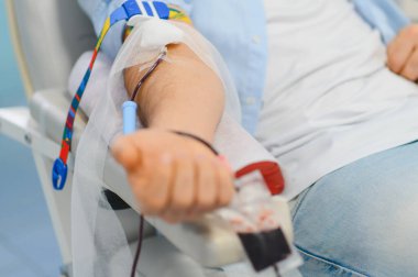 İğne ve tüplü donör kolu bir torbaya kan dolduruyor, sağlık hizmetlerine ve tıbbi bağışta bulunuyor.