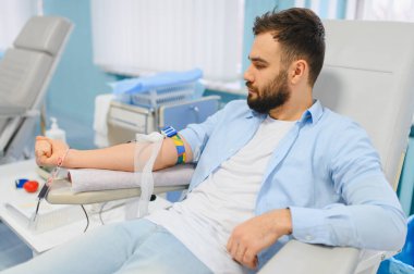 Kan nakli için kan bağışı yapan bir adam klinikte ya da hastanede tıbbi bir sandalyede oturuyor. Sağlık ve hayat kurtarma kavramı