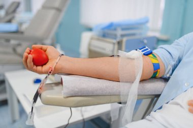 Kan bağışı yapmak, kırmızı kalp stres topu tutmak, klinikte başkalarına yardım etmek. Kol ve venipunktur kan getiriyor.