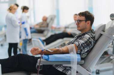 Çağdaş bir sağlık tesisinde kan bağışı yapan, tıbbi malzemelere katkıda bulunan ve başkalarına yardım eden bir adam.