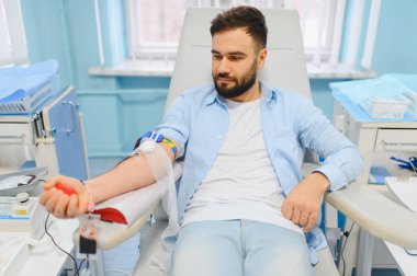 Genç bir adam modern bir klinikte kan bağışlıyor. Önemli sağlık, yardım ve gönüllü olarak hayat kurtarma kavramı.