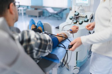 Hasta, aperatif makinesiyle kan bağışlıyor, hastane kliniğinde hemşire izleme prosedürleri uyguluyor.