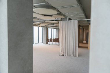 Modern ofis içi modüler alan, tavanda akustik paneller, perde bölmesi ve boş sandalyeler