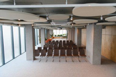 Sıra sıra sandalye, projektör ve geniş pencereli geniş boş konferans salonu, sunum veya etkinlik için hazır