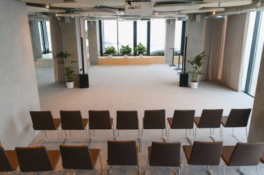 Kurumsal toplantılar ve sunumlar için kurulmuş, geniş ve çağdaş bir mekanda sahne alan boş sandalyeler.