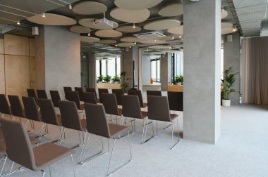 Sıralar dolusu sandalye, projektör, ekran ve akustik tavan panellerinden oluşan boş minimalist seminer odası