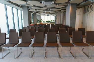 Boş bir toplantı salonunda, profesyonel bir iş etkinliği ya da seminere hazırlanan çağdaş kahverengi sandalyeler.