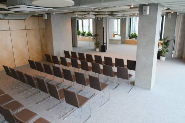 Şirket toplantısı, atölye çalışması ya da konuşmacı sunumu için kurulmuş boş sandalyelerle çağdaş olay alanı