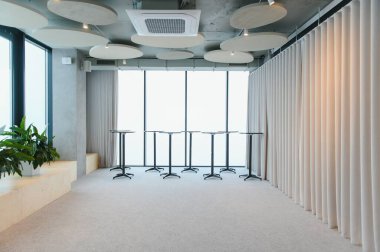 Büyük masaları, büyük pencereleri ve akustik panelleri olan modern, boş konferans odası, iş toplantıları veya etkinlikler için hazır.