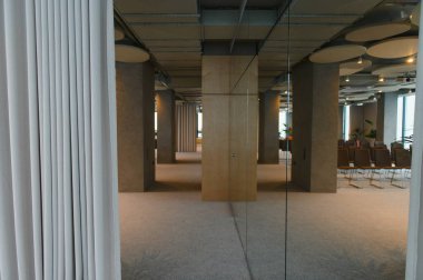 Modern ofis iç mimarisi açık bir plan, beton sütunlar, cam bölümler ve bir iş alanı