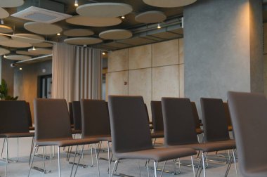 Sıralar dolusu sandalye ve modern akustik tavan panelleriyle konferans odası, etkinlik veya iş toplantısı için hazırlanıyor