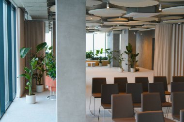 Çağdaş olay alanı koyu renkli sandalyeler ve yemyeşil bitkiler sergiliyor, sunum ve toplantılar için modern ve davetkar bir ortam yaratıyor