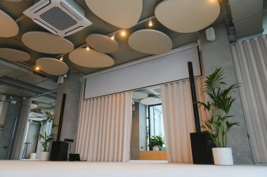 Geri çekilebilir projeksiyon ekranı, ses sistemi, akustik paneller ve iş etkinlikleri için minimalist dekor içeren çağdaş konferans salonu