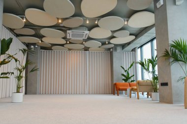 Modern ofis iç mimarisi, akustik tavan panelleri, minimalist tasarım, ve yeşil bitkiler, sakin bir dinlenme odası alanı yaratıyor.