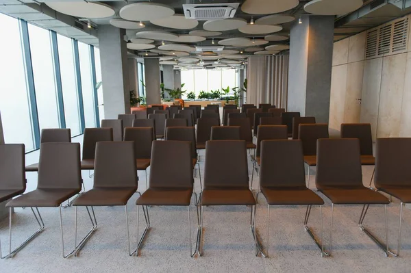 Boş bir toplantı salonunda, profesyonel bir iş etkinliği ya da seminere hazırlanan çağdaş kahverengi sandalyeler.