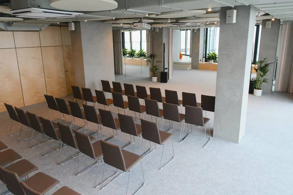 Şirket toplantısı, atölye çalışması ya da konuşmacı sunumu için kurulmuş boş sandalyelerle çağdaş olay alanı