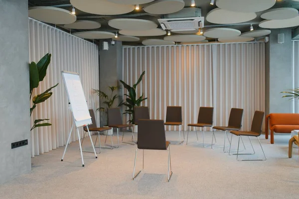 İşbirliği için tasarlanmış sandalye, akustik tavan panellerinden oluşan bir daireye sahip boş modern toplantı odası.