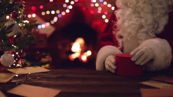 Санта Клаус сидит за столом с подарками и волшебной коробкой — стоковое видео
