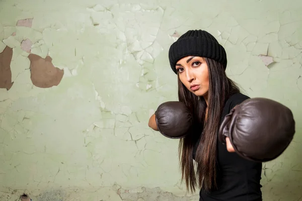 A young brunette girl is engaged in mixed martial arts. Strikes with a straight arm. Looks into the camera. Preparing for the main competition in life.