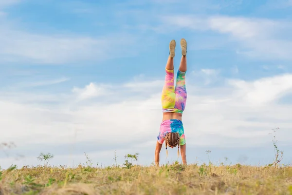 Young Girl Bright Tracksuit Performs Handstand Blue Summer Sky Legs — Stock Photo, Image