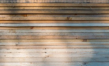 Duvarın desenli yüzeyi beyaz-kahverengi ahşap yapı tahtalarından ve düşen bir gölgeden yapılmıştır..