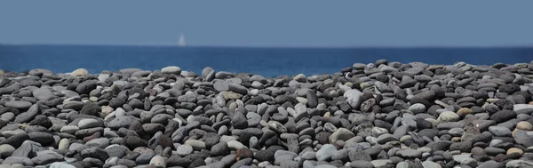 Meerblick mit Steinen und Segelschiff — Stockfoto
