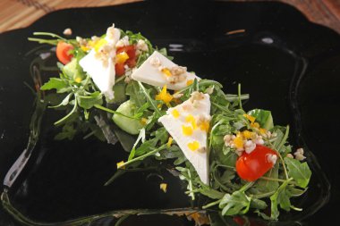 Arugula ve peynir siyah tabakta, yağlı.