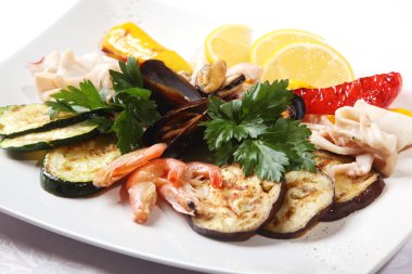 Sebzeli deniz ürünleri ve tabakta limon.
