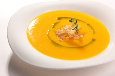 Tabağında kızarmış ekmek olan sarı çorba.