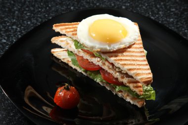 Siyah arka planda yumurta ve sebzeli sandviç.