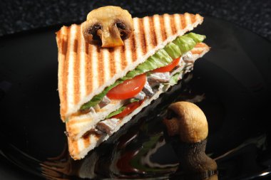 Siyah arka planda mantarlı ve sebzeli sandviç.