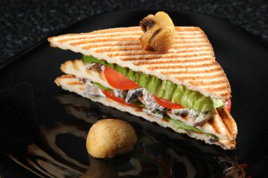 Siyah arka planda mantarlı ve sebzeli sandviç.