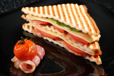 Pastırmalı sandviç ve siyah arka planda sebze.