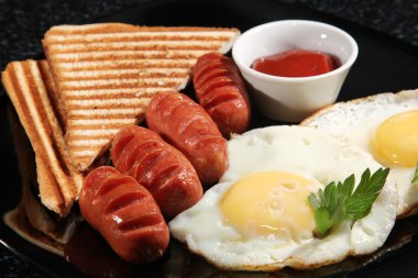 Siyah tabakta sosisli çırpılmış yumurta kahvaltısı.