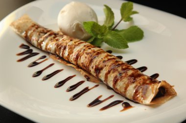 Çikolata soslu krep ve tabakta dondurma.