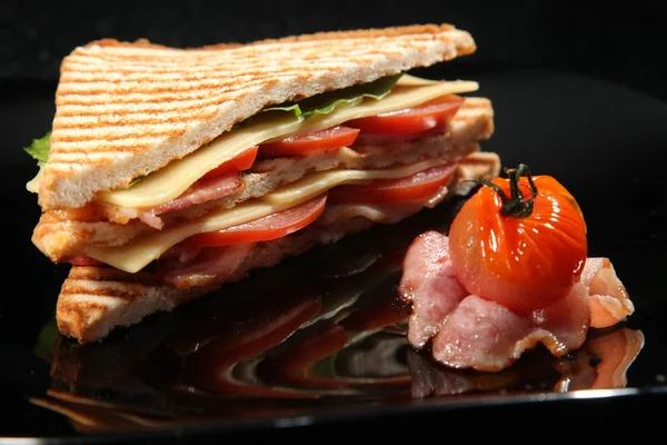 sandwich with Bacon and vegetables on black background